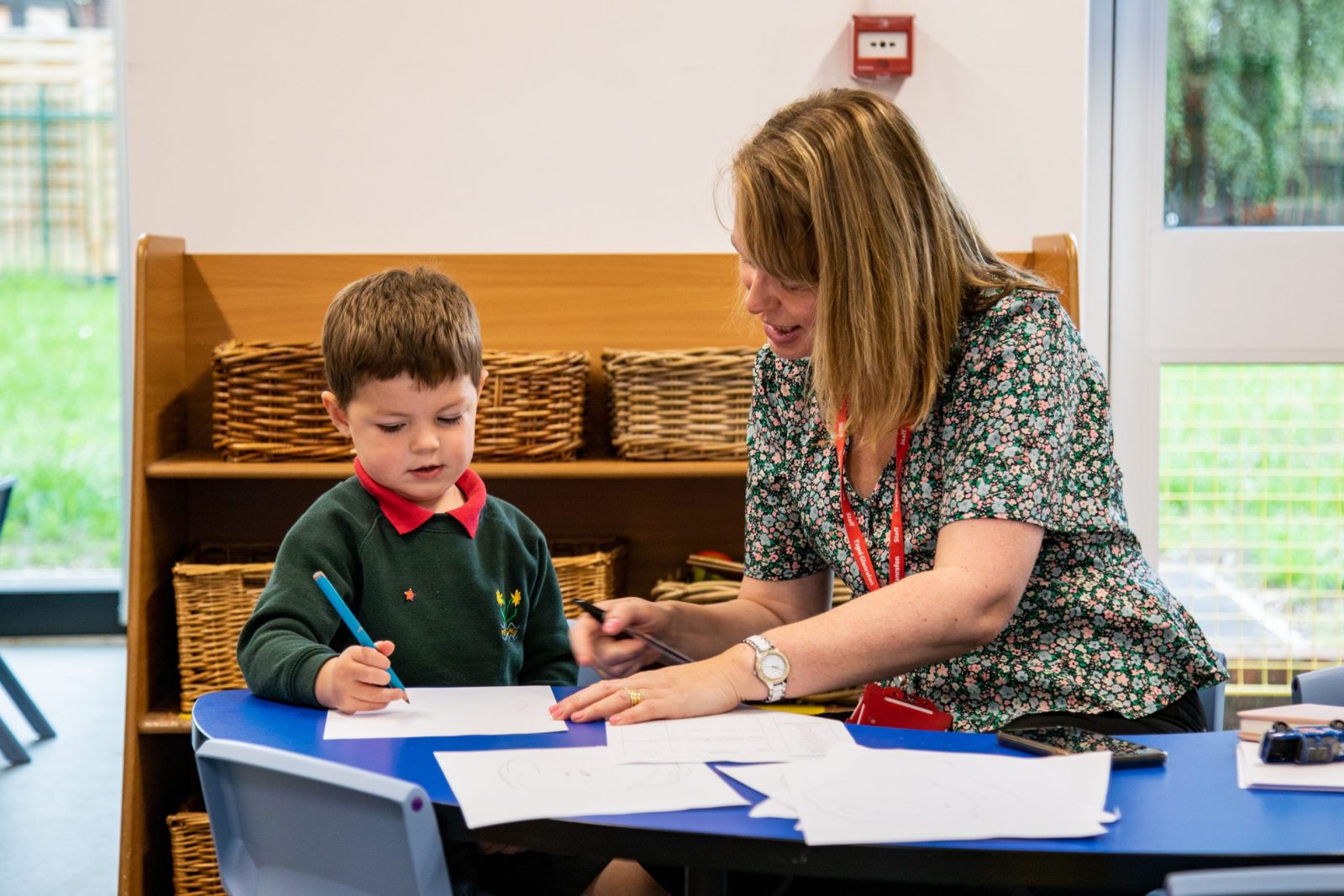 A teacher working one-on-one with a young student at a table, surrounded by baskets.