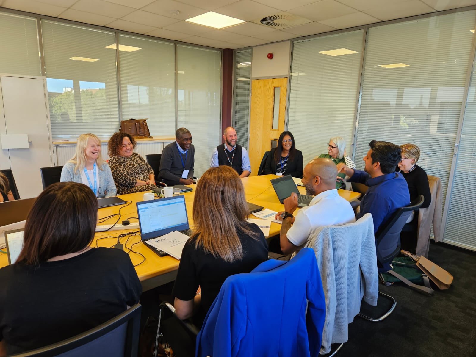 A group of professionals sitting around a table in a meeting room, engaged in a discussion.