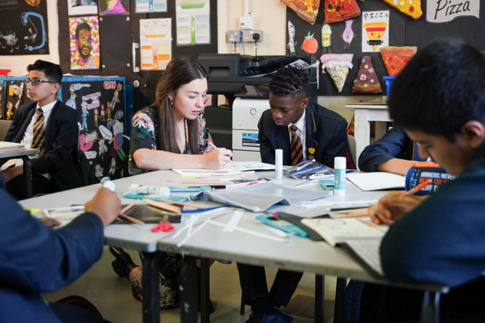Students in school uniforms engaged in a classroom activity with books on their desks.