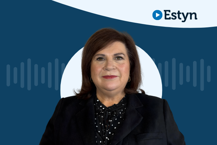 Portrait of an individual with shoulder-length brown hair, wearing a black jacket and a dotted blouse, standing in front of a circular graphic with a blue Estyn logo and sound wave patterns.